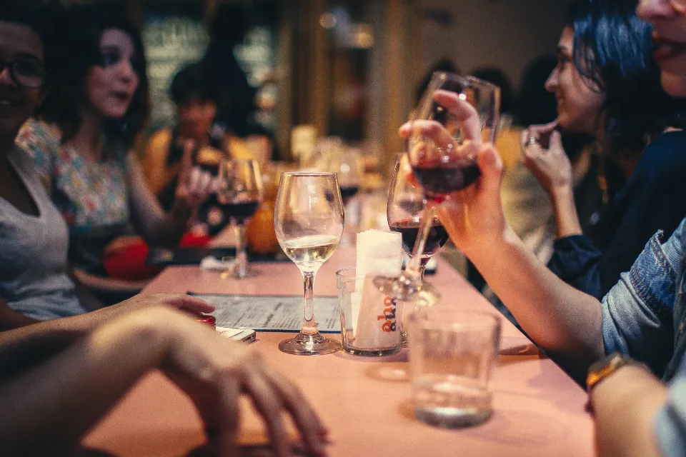 A group of friends laughing together over drinks at a restaurant table